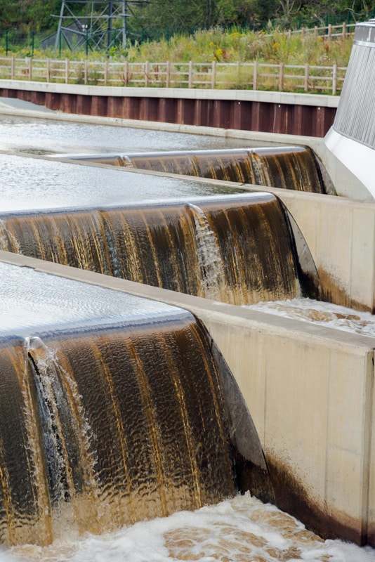 Several large concrete dams in a row with water flowing over them.