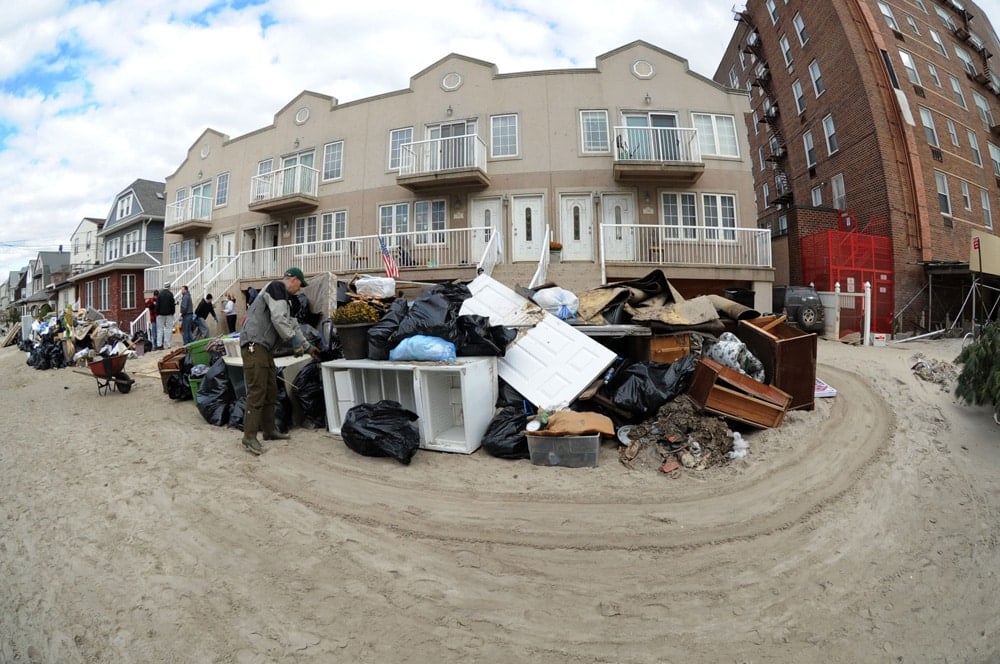 Debris collected by workers outside of a group of buildings after a disaster.
